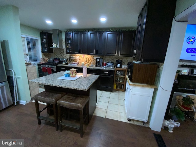 3227 Woodring Ave, Baltimore, MD 21234 - kitchen with dark cabinets, backsplash, stainless steel range with gas cooktop, a center island, and a kitchen bar