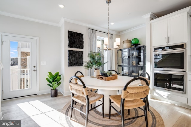 dining area featuring crown molding, baseboards, a chandelier, and light wood-style floors