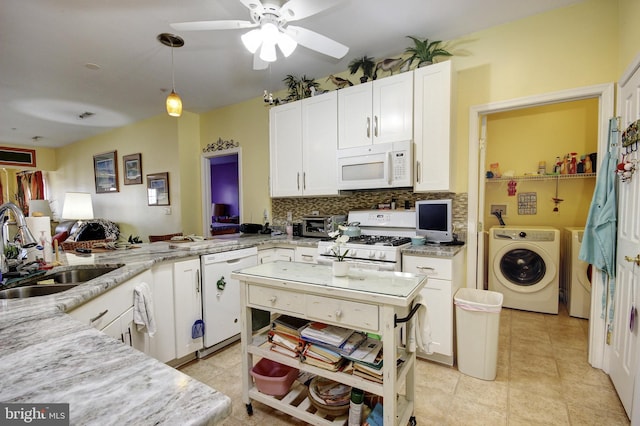 kitchen with white appliances, tasteful backsplash, washer / dryer, white cabinets, and a sink