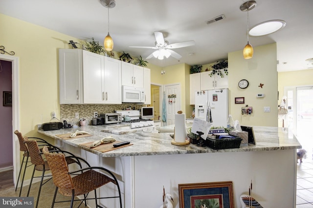 kitchen featuring a peninsula, white appliances, white cabinetry, visible vents, and tasteful backsplash