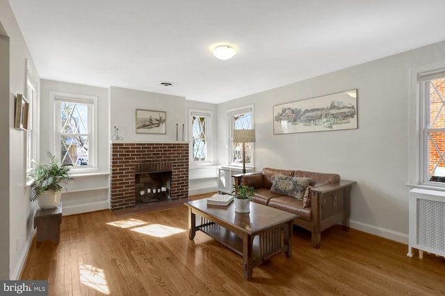 living area with visible vents, radiator, baseboards, a fireplace, and wood finished floors