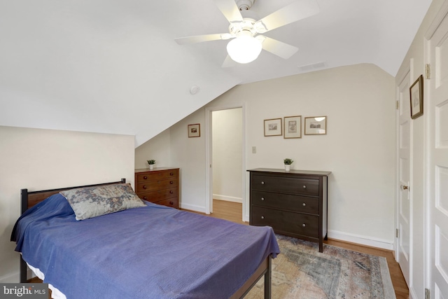 bedroom featuring visible vents, baseboards, vaulted ceiling, wood finished floors, and a ceiling fan