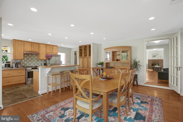 dining room with recessed lighting, a brick fireplace, and wood finished floors