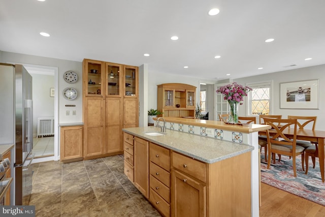 kitchen featuring light stone countertops, radiator heating unit, recessed lighting, high end fridge, and a sink