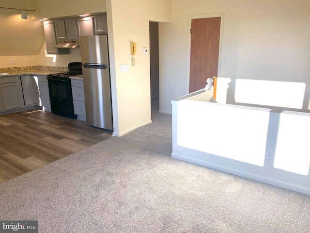 kitchen featuring under cabinet range hood, gray cabinets, freestanding refrigerator, black electric range oven, and dark colored carpet