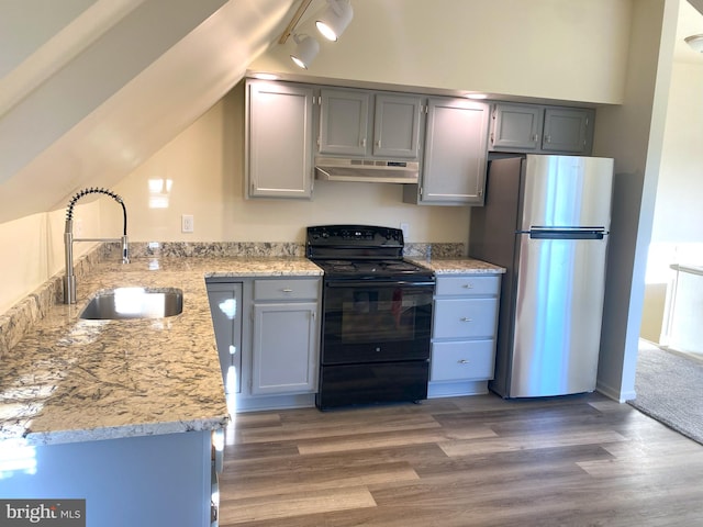 kitchen with wood finished floors, freestanding refrigerator, under cabinet range hood, black range with electric cooktop, and a sink