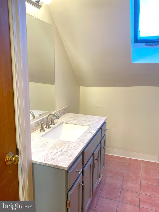 bathroom featuring vanity, baseboards, vaulted ceiling, and tile patterned floors