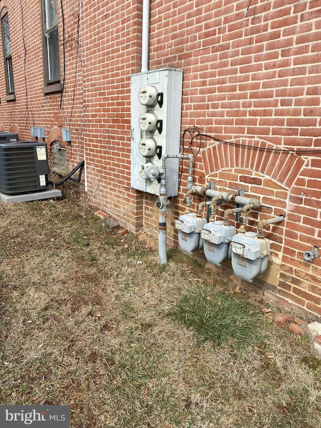 details featuring central AC, brick siding, and gas meter