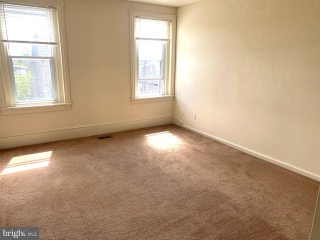 unfurnished room with baseboards, plenty of natural light, visible vents, and carpet flooring