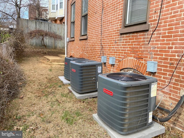 details featuring brick siding, cooling unit, and fence