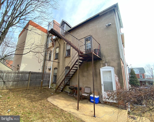 back of house with stairs, fence, and stucco siding