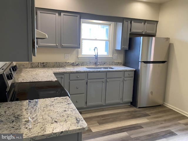 kitchen featuring under cabinet range hood, appliances with stainless steel finishes, a sink, and gray cabinetry