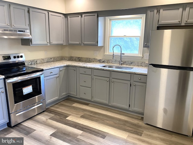 kitchen featuring appliances with stainless steel finishes, gray cabinets, a sink, and under cabinet range hood