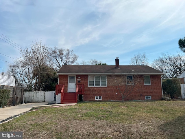 view of front facade featuring a chimney, fence, a front lawn, and brick siding