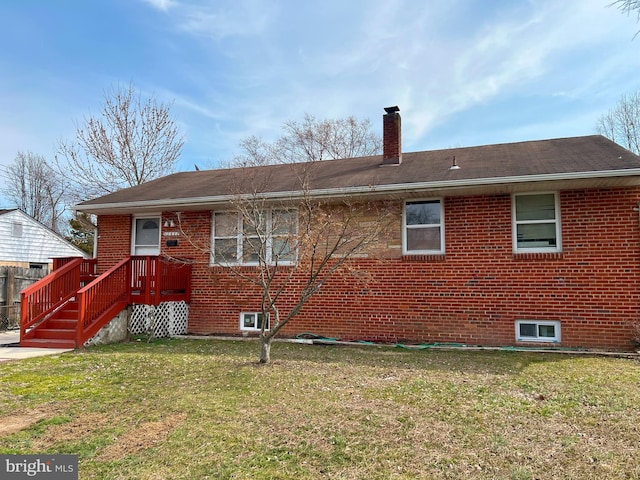 rear view of property with brick siding, a yard, and a chimney