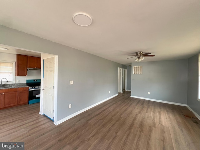 unfurnished living room featuring dark wood-type flooring, a sink, a ceiling fan, visible vents, and baseboards