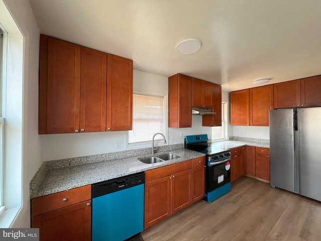 kitchen featuring under cabinet range hood, stainless steel appliances, a sink, light wood-style floors, and light countertops