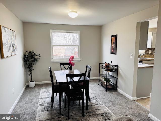 dining area featuring light carpet and baseboards