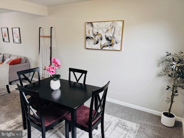 dining area with baseboards and light colored carpet