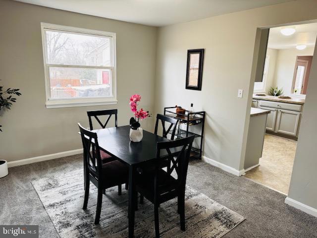 dining area featuring light carpet and baseboards