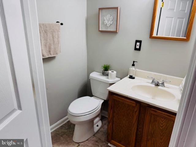 half bath with toilet, vanity, and tile patterned floors