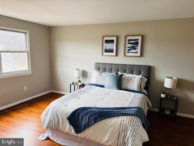 bedroom featuring visible vents, baseboards, and wood finished floors