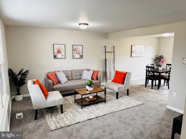 carpeted living area featuring baseboards