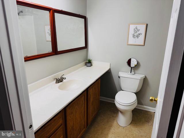 bathroom featuring toilet, vanity, and baseboards