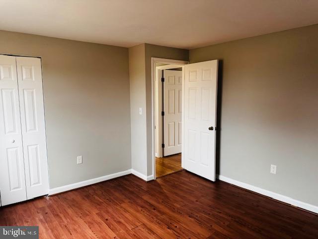 unfurnished bedroom with a closet, wood finished floors, and baseboards