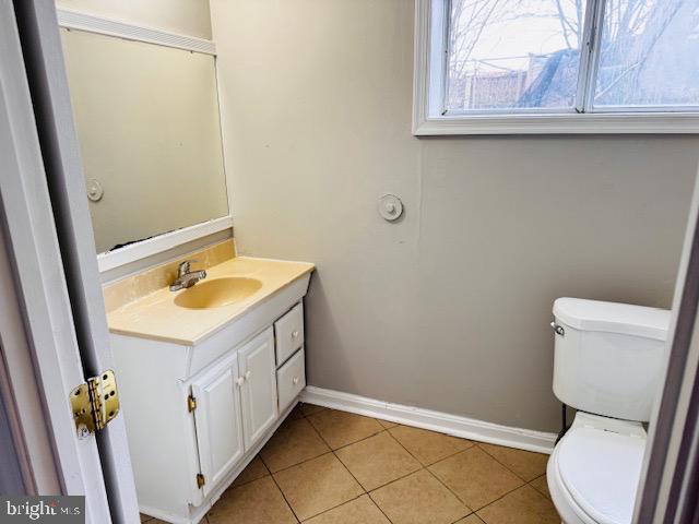 half bathroom featuring toilet, baseboards, and tile patterned floors