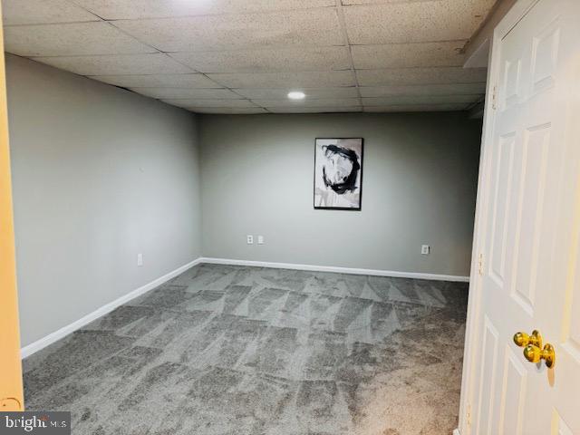 finished basement with carpet, a drop ceiling, and baseboards