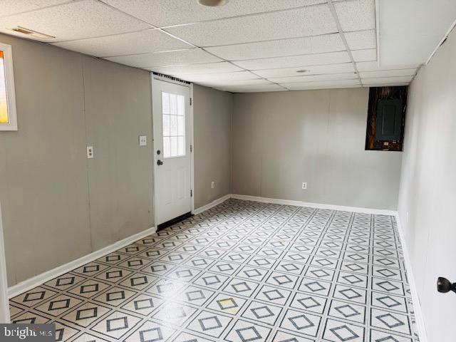 basement with a drop ceiling and baseboards