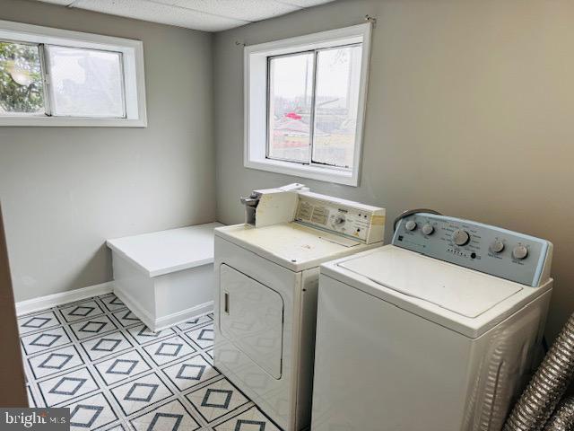 washroom featuring laundry area, baseboards, and separate washer and dryer