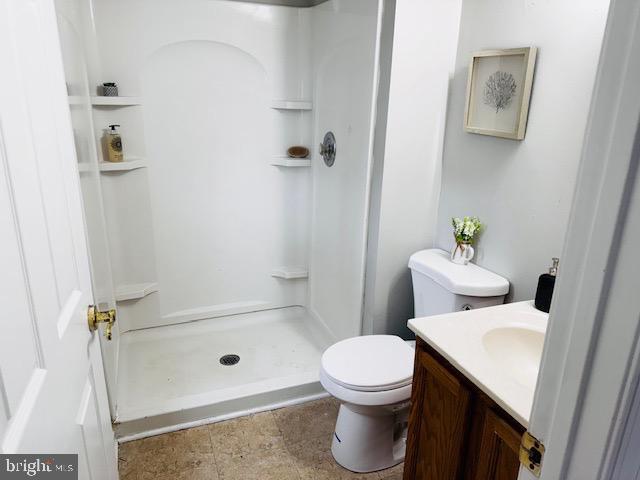 full bathroom with toilet, a stall shower, and vanity