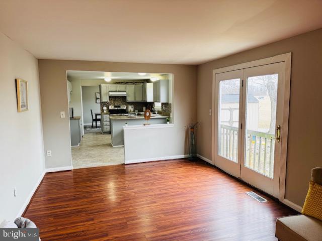 unfurnished living room with visible vents, light wood-style flooring, and baseboards