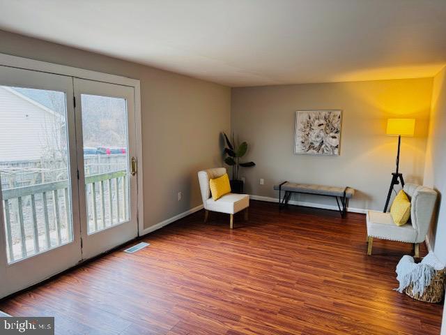 sitting room with wood finished floors, visible vents, and baseboards