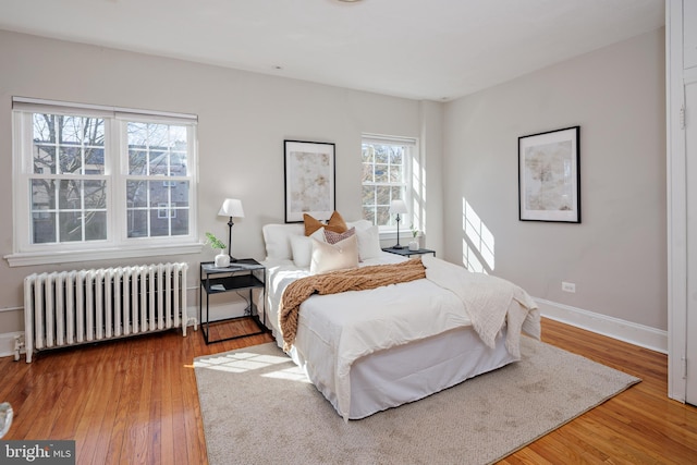 bedroom featuring radiator heating unit, baseboards, and wood finished floors