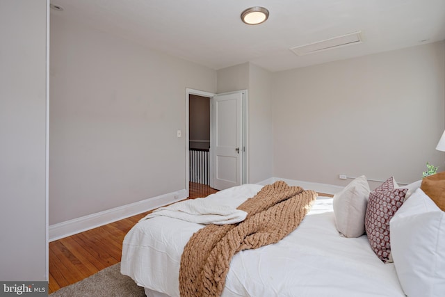 bedroom featuring attic access, baseboards, and wood finished floors