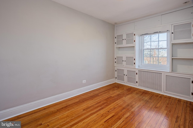 spare room with hardwood / wood-style floors and baseboards