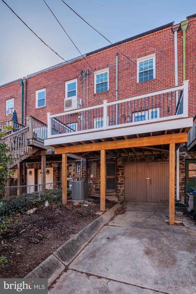 back of house featuring central air condition unit, a carport, and brick siding