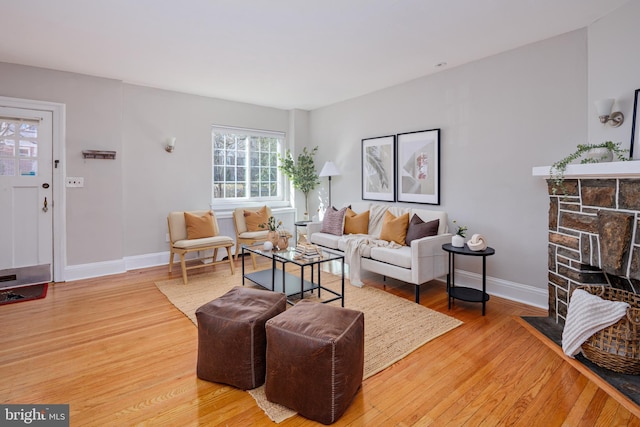 living area featuring baseboards, a fireplace, and light wood-style floors