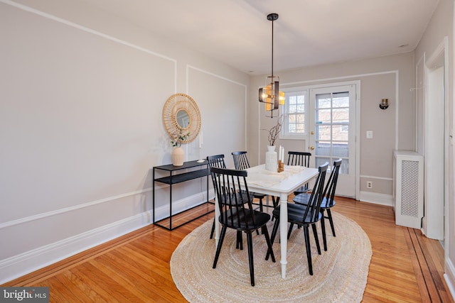 dining room with light wood-style floors, radiator heating unit, and baseboards