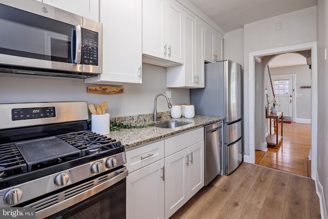 kitchen with light wood-style floors, appliances with stainless steel finishes, white cabinets, and a sink