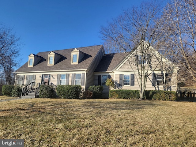 cape cod house with a front lawn, fence, and a shingled roof