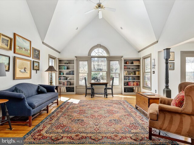 living room with ceiling fan, light wood-style floors, a wealth of natural light, and high vaulted ceiling