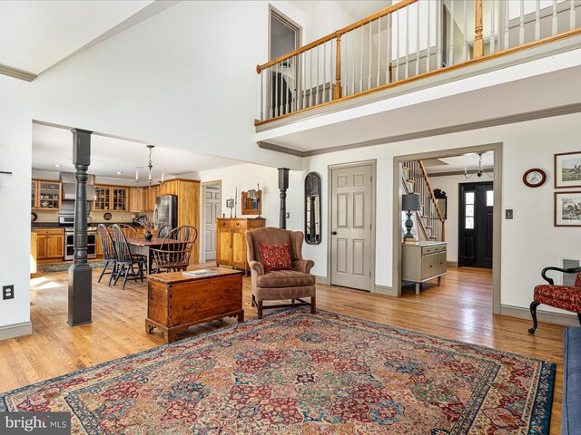 living area with baseboards, light wood-style floors, a high ceiling, and stairs