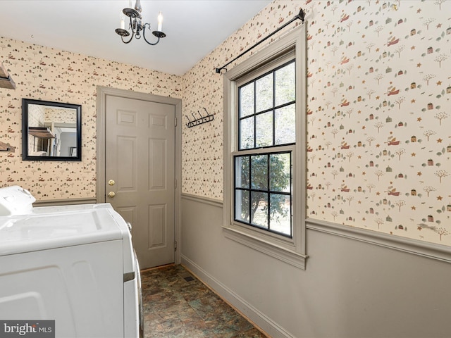 clothes washing area featuring washer and clothes dryer, laundry area, wallpapered walls, and a wainscoted wall