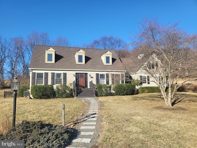 new england style home featuring a front yard and roof with shingles