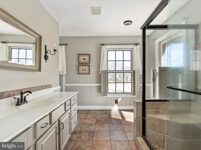 full bath featuring visible vents, plenty of natural light, vanity, and a wainscoted wall