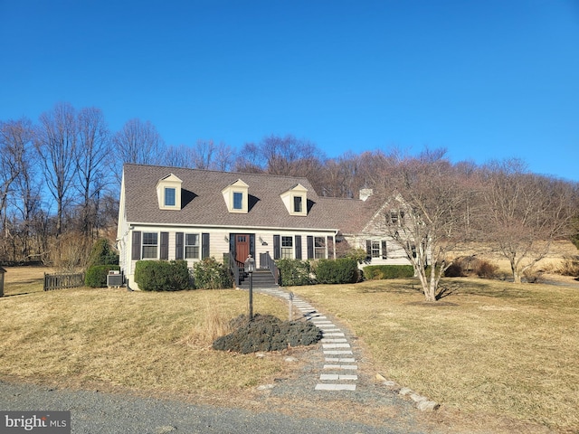 cape cod home with roof with shingles, central AC unit, and a front lawn